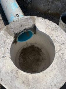 A cement pipe with blue water coming out of it.