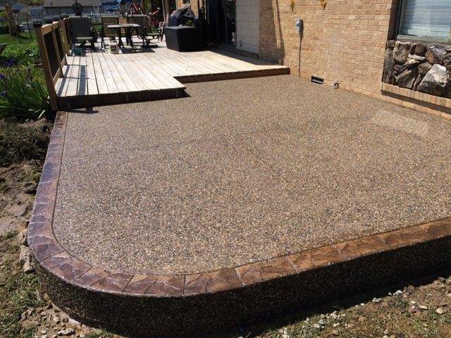 A patio with a concrete slab and a wooden deck.