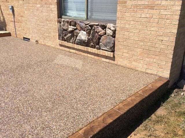 A patio with rocks and concrete on the side