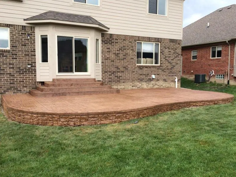 A patio with grass and brick walls in the back yard.