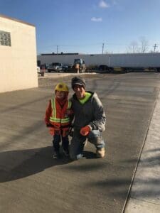 A man and child in construction gear pose for the camera.