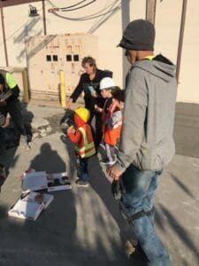 A group of people standing around on the sidewalk.