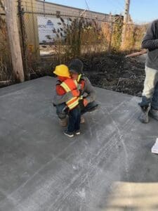 A young boy wearing an orange vest and yellow safety jacket.