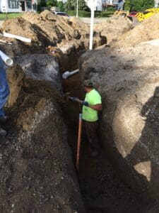 A man in yellow shirt standing next to pipe.