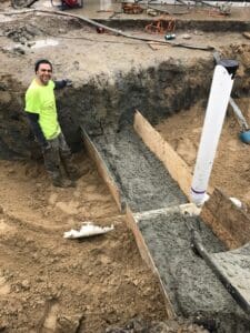 A man standing in the dirt next to a trench.