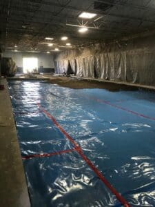 A pool with blue tarps covering it and red ropes.