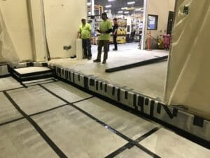 Two men standing in a room with some concrete floors